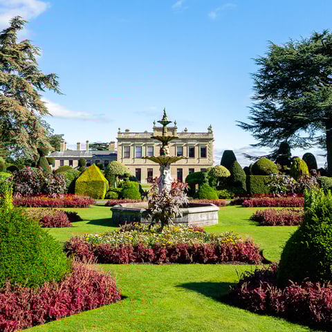 A view of Brodsworth Hall from the gardens filled with colourful flowers.