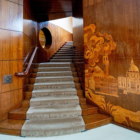 A staircase with lined wooden walls that include a detailed display of some grand buildings
