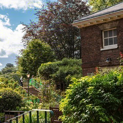 A view of the gardens at Kenwood with a brick building in the foreground.