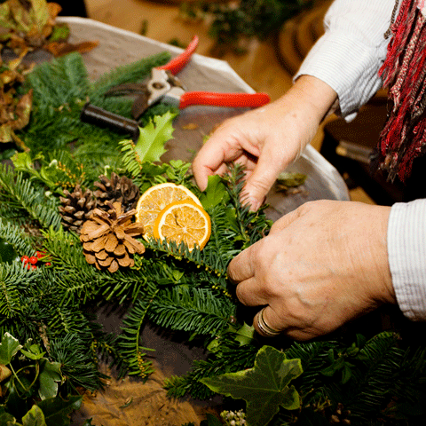 A close-up photograph of someone making a Christmas wreath.