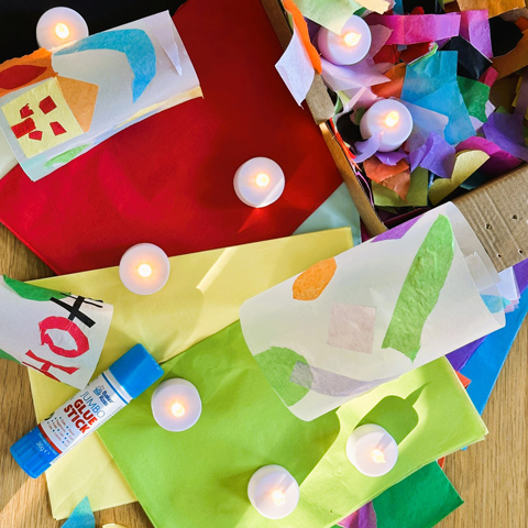 A lantern making workshop set up with colourful paper lanterns next to a box of coloured tissue paper.