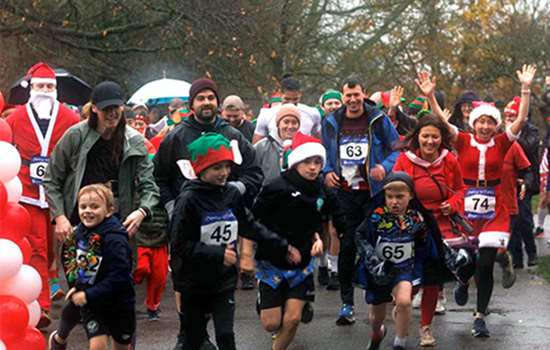A group of runners start a race, some wearing Santa hats, on a rainy, wintry day A group of runners start a race, some wearing Santa hats, on a rainy, wintry day