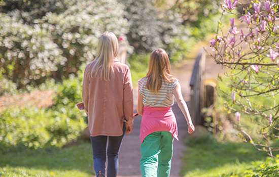 Two women walk away from the camera down a garden path Two women walk away from the camera down a garden path