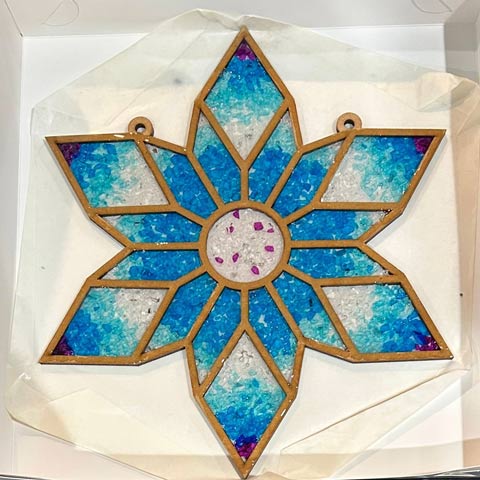 A handmade colourful faux stained-glass suncatcher in a star-like shape.