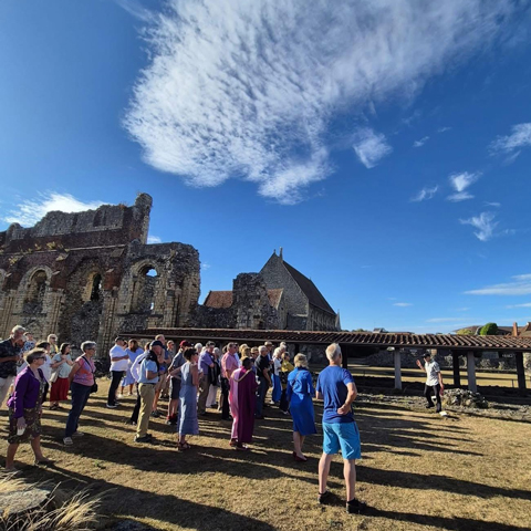 A group of people on a tour of St Augustine's Abbey on a sunny day.