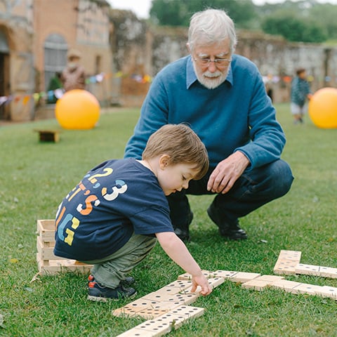 A boy and a man play with oversized dominoes