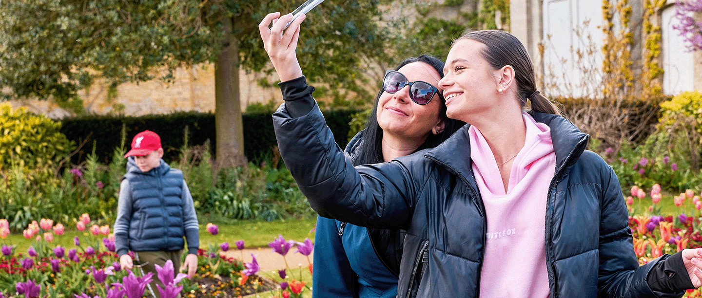 Photo of a mother and daughter taking a selfie and surrounded by colourful flowers in the walled garden at Wrest Park