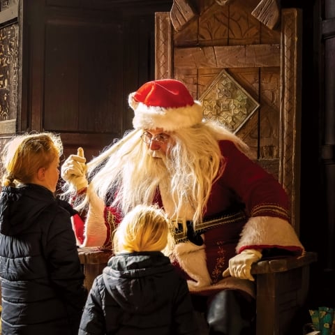 Father Christmas gives out presents to two children in the Gatehouse at Kenilworth Castle.