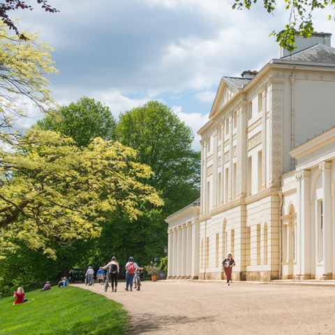 A side on view of Kenwood House, surrounded by greenery. 