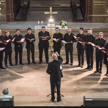 A group of men sing in a choir in a church altar.
