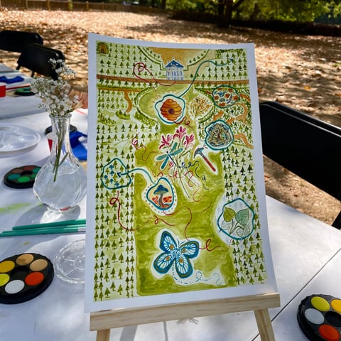 A colourful painting on a canvas stand on a table in the gardens at Marble Hill.
