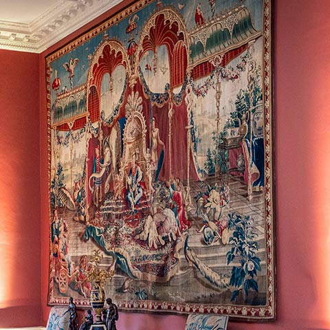A fine tapestry hangs on a red wall