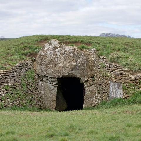 A view of the stone archway at Stoney Littleton Long Barrow covered by grass.