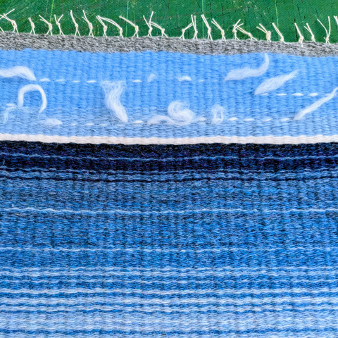 A close up of a colourful blue and white woven fabric.