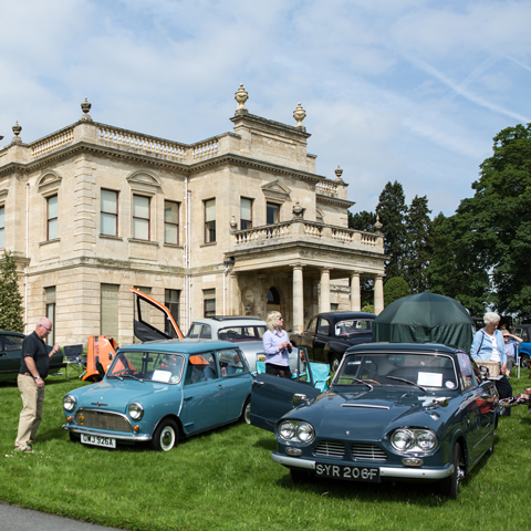 A view of the Classic Car Show at Brodsworth Hall, with a view of various classic cars in front of the building on the lawn.