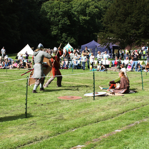 A medieval fight re-enactment in the grounds of Furness Abbey with a large crowd gathered.
