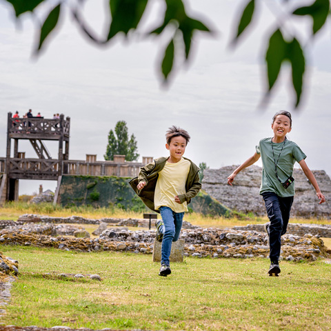 Two children running in front of Richborough Roman Fort.